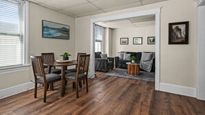 A dining area with a wooden table and chairs, a painting on the wall, and a view into a living room with a sofa and a coffee table. - 2BR Near Duluth + Spacious & Work‑Friendly (Superior)