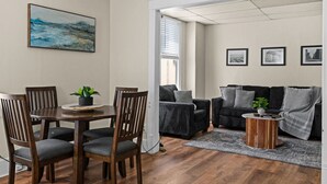 A dining area with a wooden table and chairs, a small potted plant, and a painting on the wall. - 2BR Near Duluth + Spacious & Work‑Friendly (Superior)
