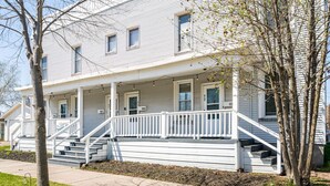 A two-story house with a front porch, a staircase, and a number '921' on the house. - 2BR Near Duluth + Spacious & Work‑Friendly (Superior)