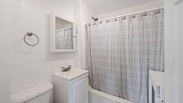 Een badkamer met toilet, wastafel, spiegel en douchegordijn.