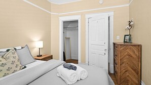 Une chambre à coucher comprenant un lit, une table de chevet, une lampe et une commode en bois.