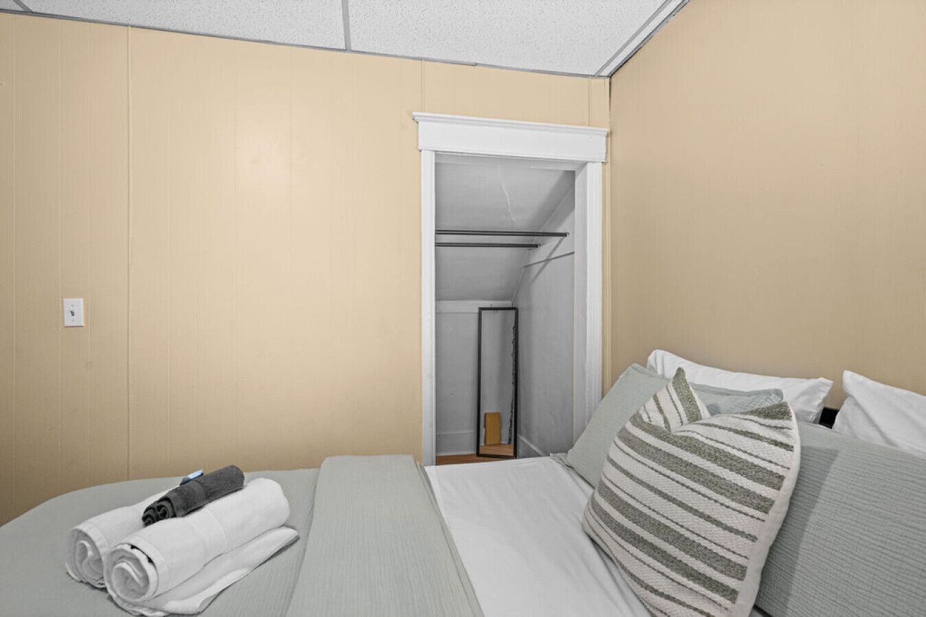 A hotel room with a bed, a bathroom visible through a door, and a small table with towels.