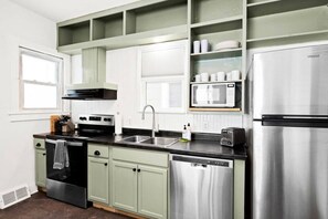 A kitchen with a stainless steel refrigerator, a microwave, a sink, and a stove.