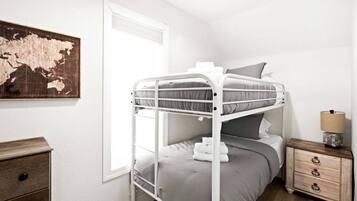 A bunk bed room with a wooden dresser, a lamp, and a world map on the wall.