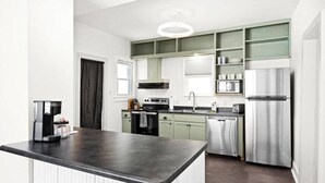 Una cocina moderna con una isla central, electrodomésticos de acero inoxidable y armarios de color verde claro.