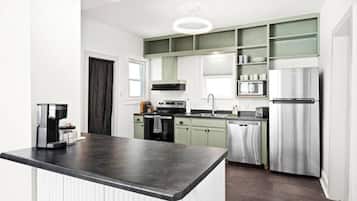A modern kitchen with a central island, stainless steel appliances, and a green backsplash.