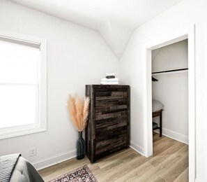 A room with a wooden cabinet, a window, a door leading to another room, and a patterned rug.