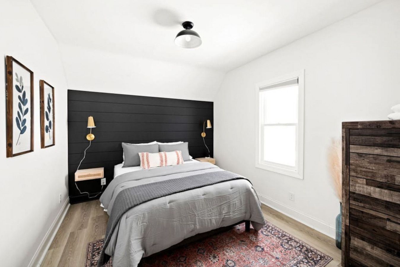 A bedroom with a bed, bedside lamps, a window, and a wooden dresser.
