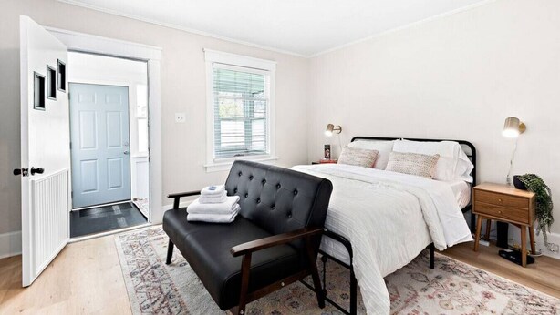 A bedroom with a bed, bedside tables, a chair, a door, and a window. - Clough · Quaint Cottage on Clough (Superior)