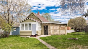 A single-story house with a front porch, a small attached garage, and a fenced backyard. - Clough · Quaint Cottage on Clough (Superior)