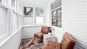 A corner room with white walls, two windows, a patterned rug, and two brown leather chairs. - Clough · Quaint Cottage on Clough (Superior)