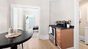 A modern kitchen with a black countertop, stainless steel appliances, and a wooden dining table. - Clough · Quaint Cottage on Clough (Superior)