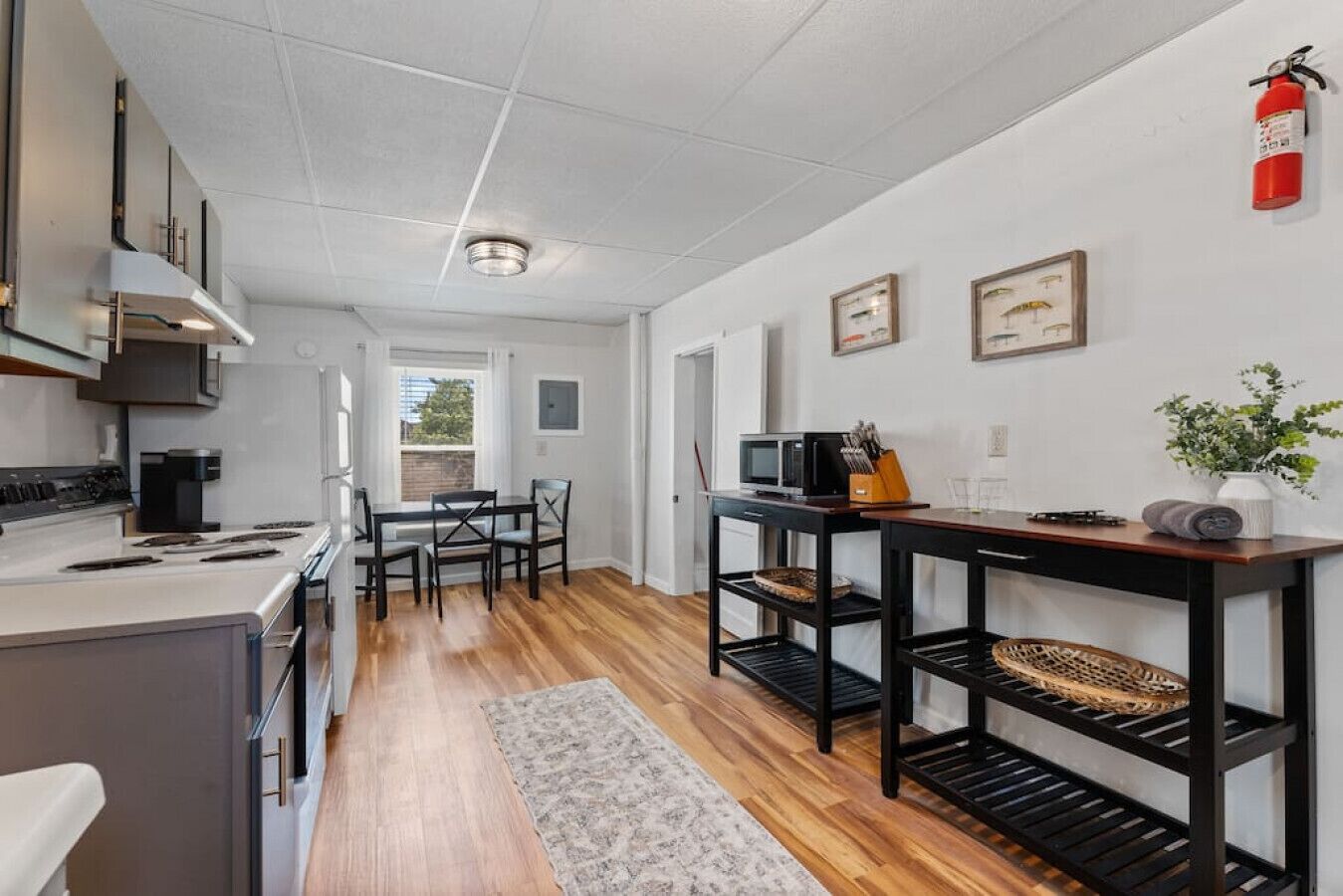 A modern kitchen with a stove, microwave, and dining area with chairs and a table.