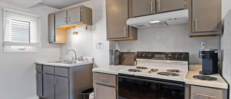 A compact kitchen with a stove, sink, and cabinets.