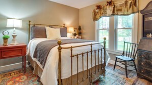 A bedroom with a bed, bedside tables, a chair, a dresser, and a window with curtains. - Updated Cotter Cottage: Walk to White River! (Cotter)