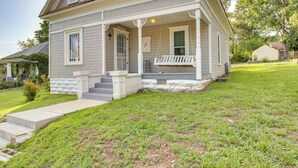 A two-story house with a front porch, a small front yard, and a visible garage. - Updated Cotter Cottage: Walk to White River! (Cotter)