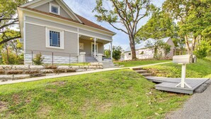 A two-story house with a front porch, a mailbox, and a stone retaining wall. - Updated Cotter Cottage: Walk to White River! (Cotter)