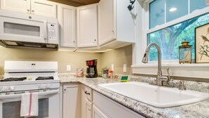 A kitchen with white cabinets, a stainless steel sink, a microwave, and a stove. - Updated Cotter Cottage: Walk to White River! (Cotter)