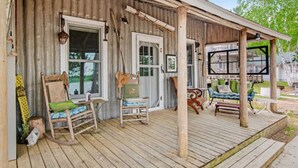 Een rustiek houten terras met schommelstoelen en een overdekte zithoek.
