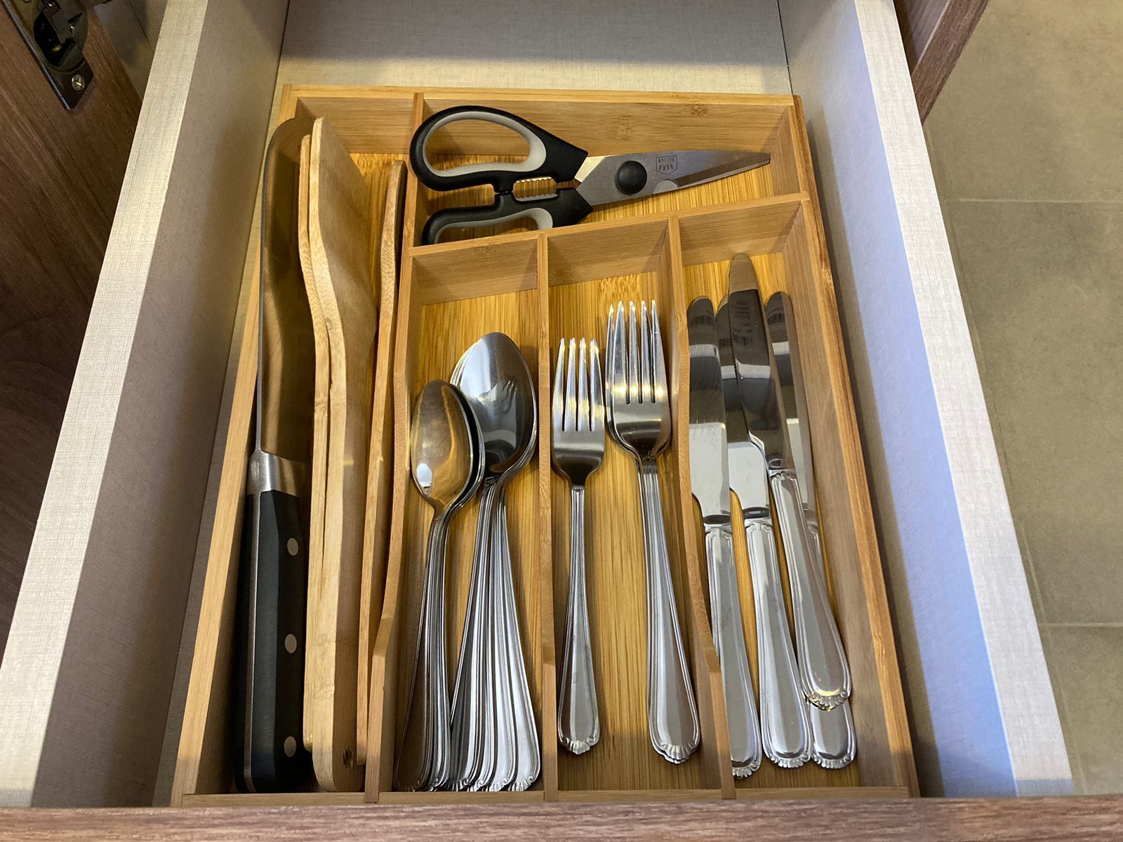 A drawer with neatly organized silverware, including forks, spoons, and a knife.