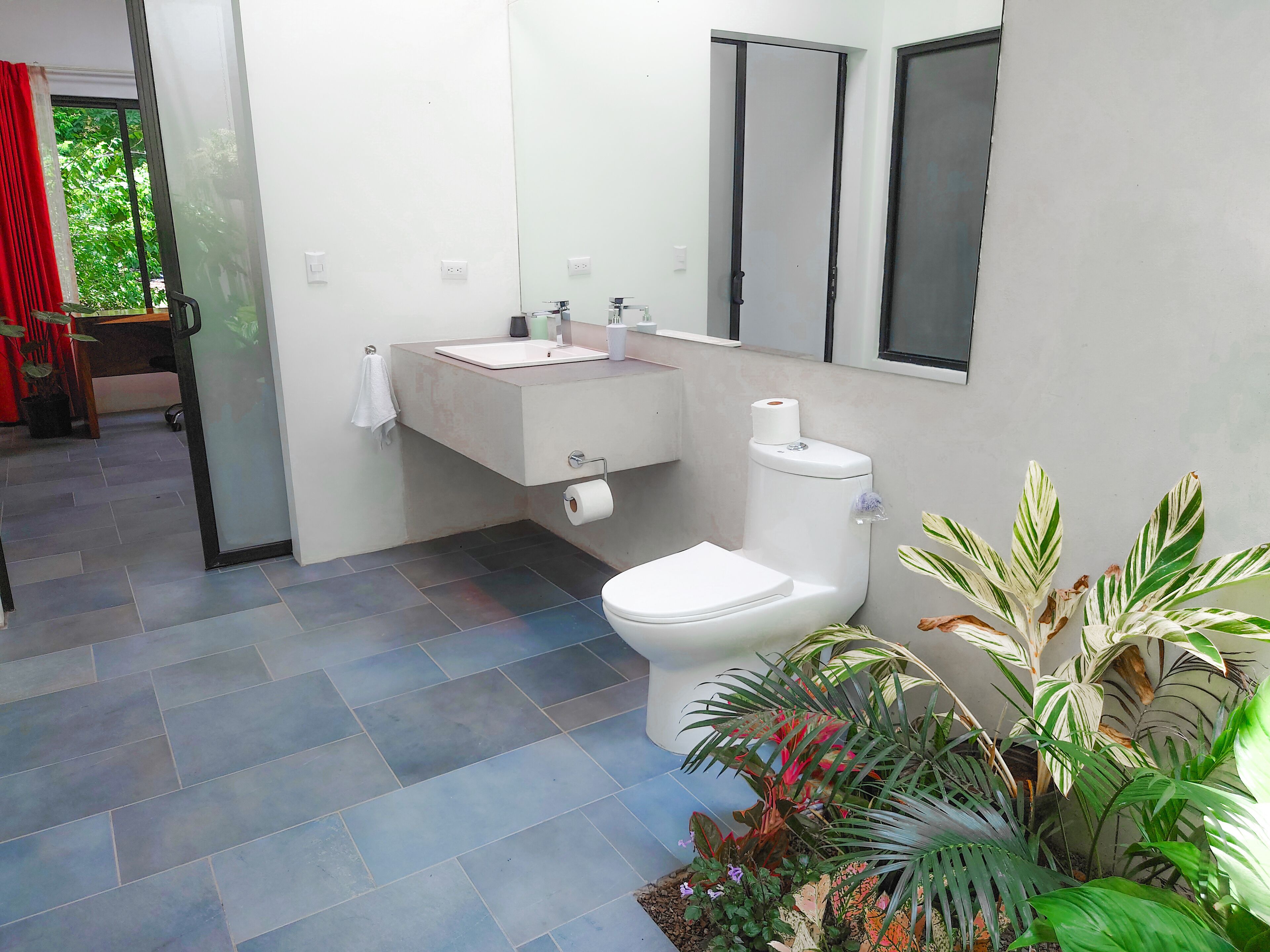 Un baño moderno con inodoro, lavabo y espejo.