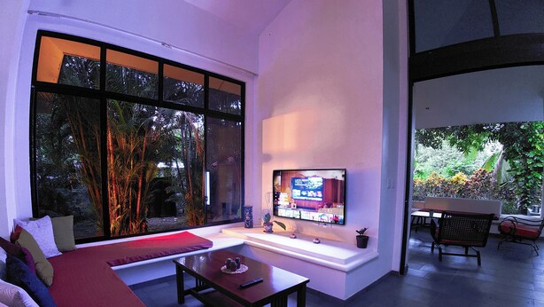 Ein modernes Wohnzimmer mit großem Fenster, Flachbildfernseher, Sofa und Couchtisch.