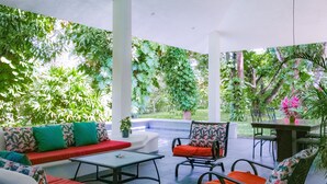 Eine Außenpatio mit einer weißen Sofagarnitur, einem Esstisch mit Stühlen und einem Blumentopf.