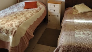 Ein Zimmer mit zwei Betten, einem Nachttisch und einem kleinen Schrank.
