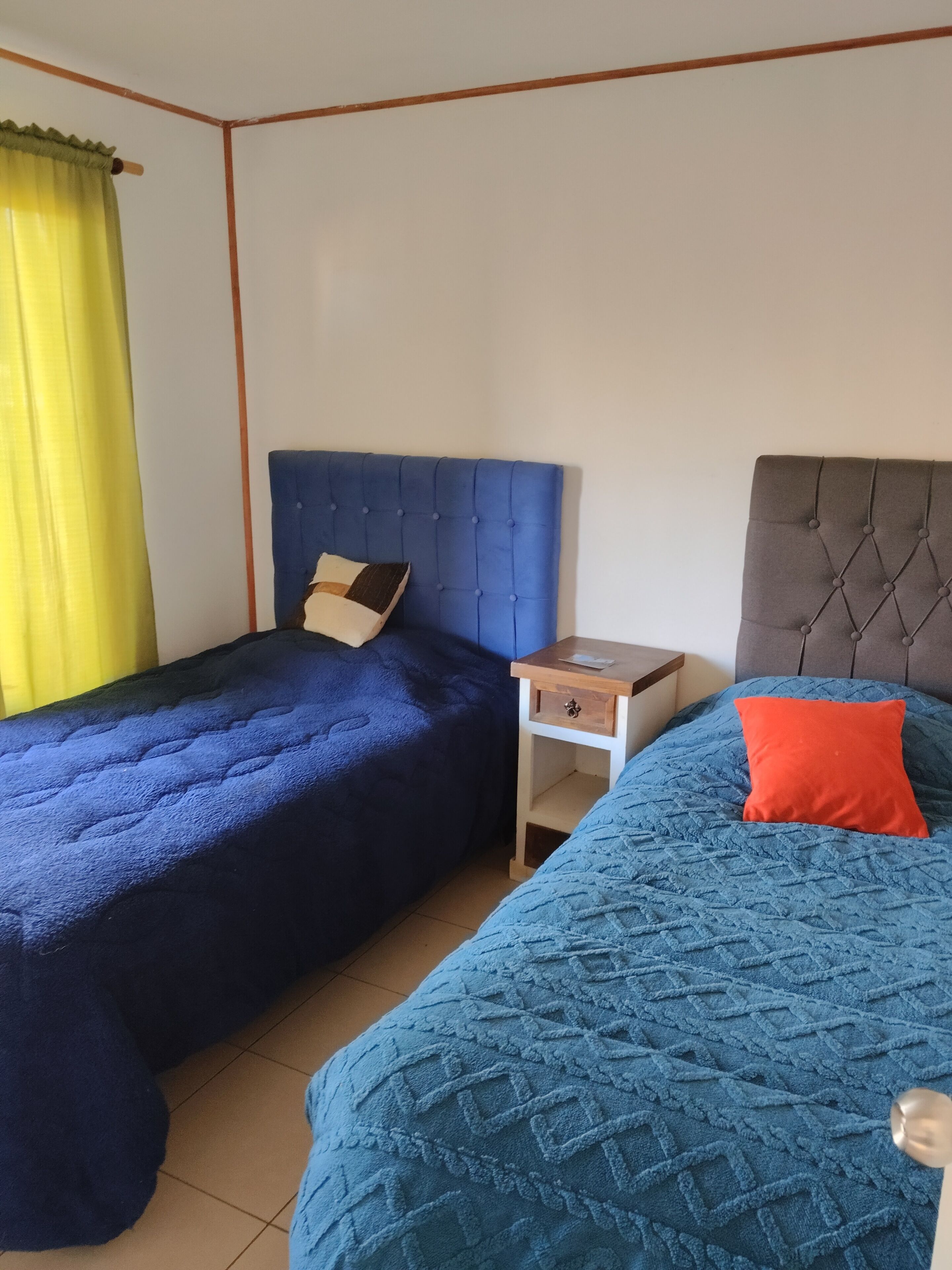 Une chambre avec deux lits, une table de chevet et une fenêtre avec des rideaux.