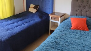 Ein Zimmer mit zwei Betten, einem Nachttisch und einem Fenster mit Vorhängen.