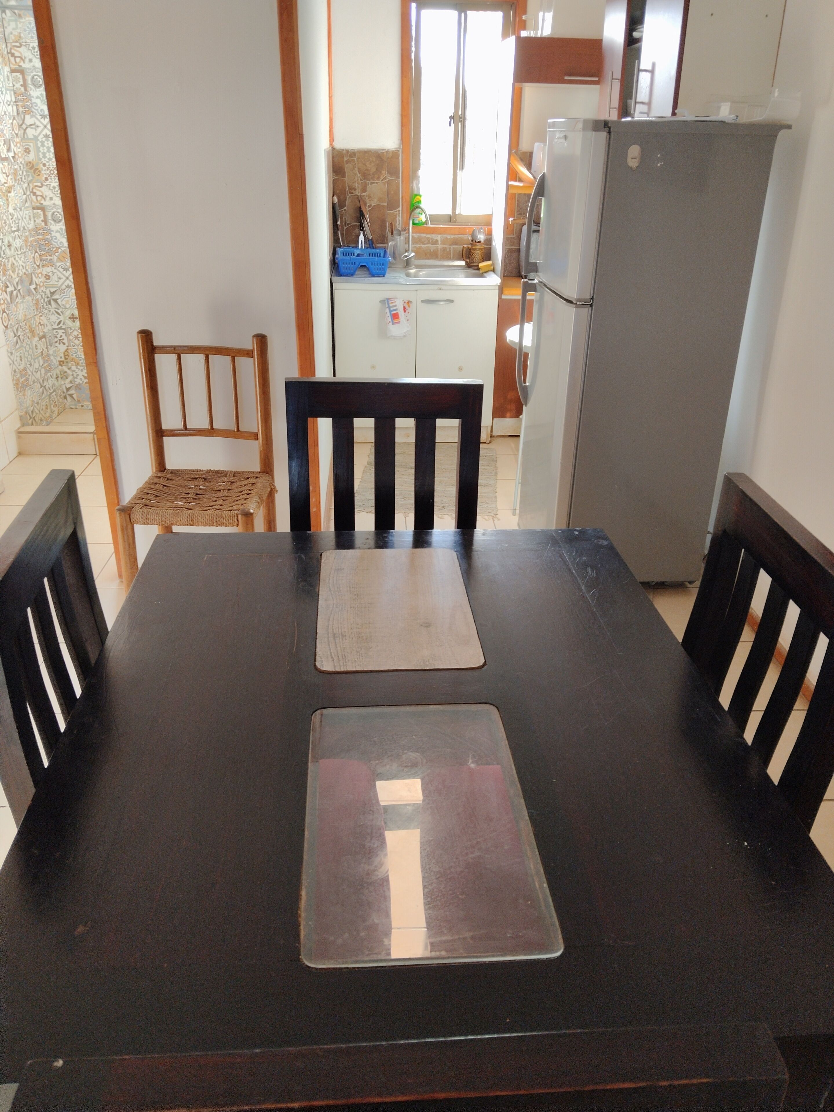 Une table à manger avec deux sets de table, entourée de quatre chaises en bois.
