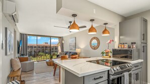 Una cocina moderna con una isla central, electrodomésticos integrados e iluminación colgante.