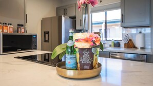 Una encimera de cocina con una botella de agua Pellegrino, una caja de Mini Bites Lemon y una orquídea en maceta.