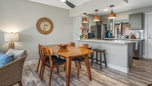 Una cocina moderna con una isla central, iluminación colgante y ventilador de techo.
