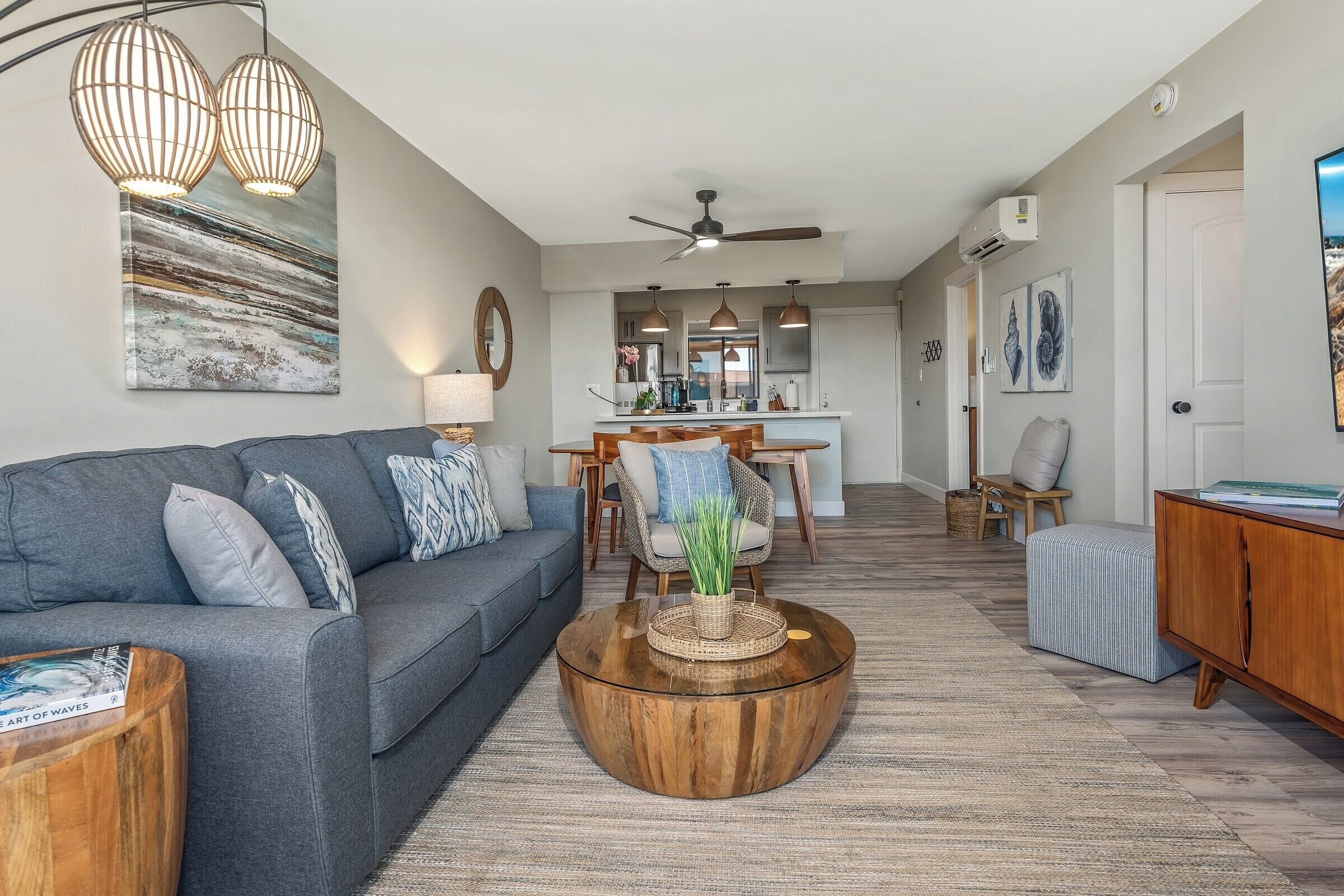 A modern living room with a grey sofa, a wooden coffee table, and a dining area with a white table and chairs.