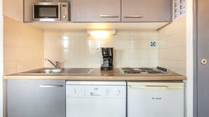 A compact kitchen with a microwave, coffee maker, stove, and dishwasher. - Appartement 6 pers, vue montagne avec terrasse (Chamrousse)
