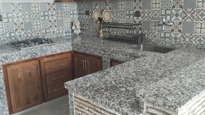 Una cocina con encimeras de granito, armarios de madera y azulejos decorativos en la salpicadero.