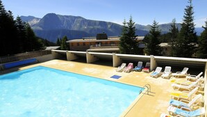 A swimming pool with lounge chairs and a mountain view. - Superbe logement 6 pers à Chamrousse (Chamrousse)