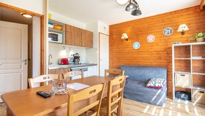 A cozy kitchen with wooden cabinets, a microwave, and a coffee maker. There's a dining table with chairs and a small rug. - Superbe logement 6 pers à Chamrousse (Chamrousse)