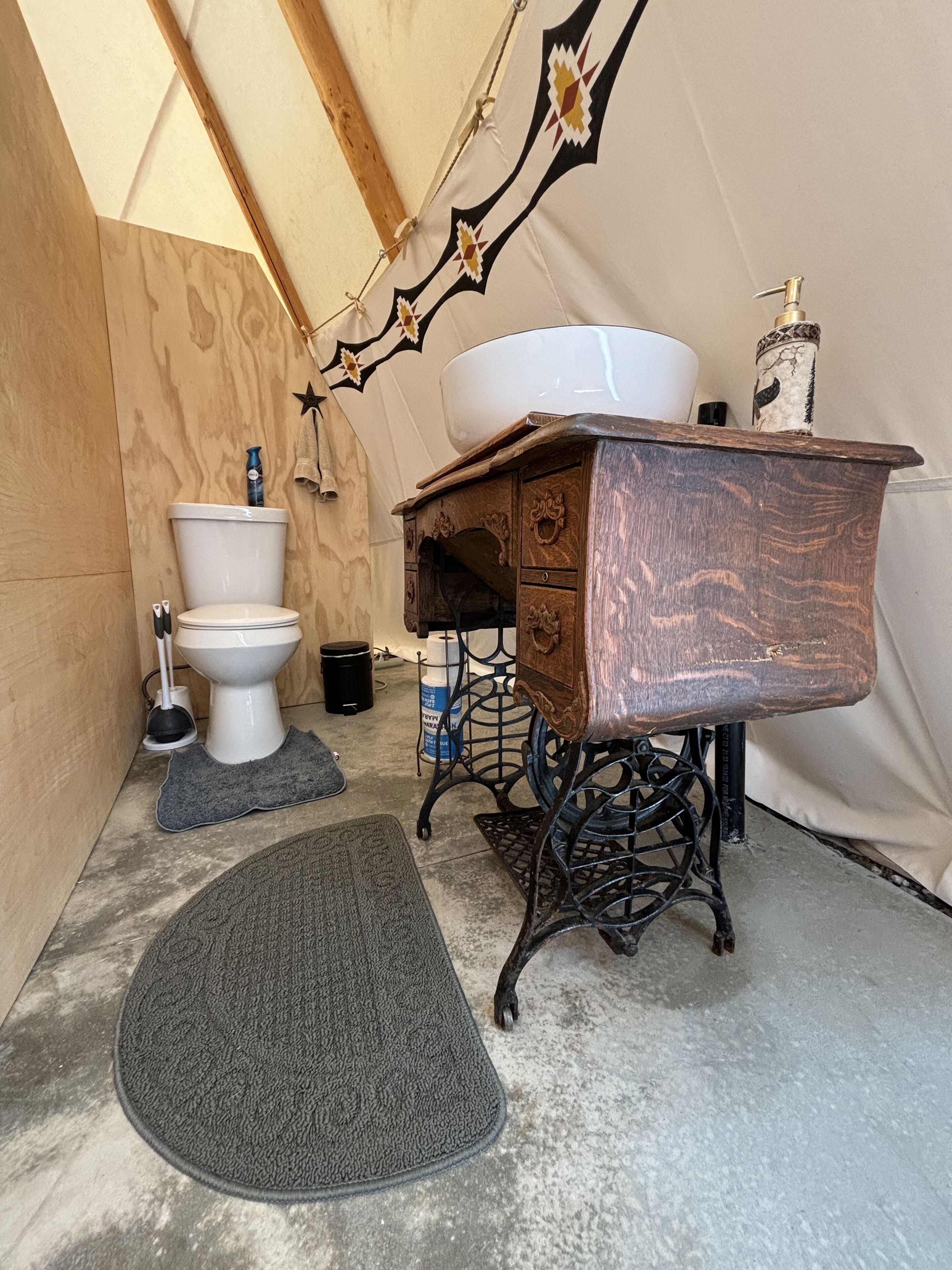 A compact, rustic bathroom with a wooden vanity, a white sink, and a toilet.
