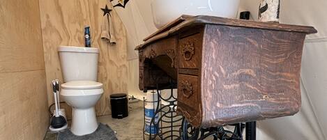 A compact, rustic bathroom with a wooden vanity, a white sink, and a toilet.