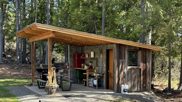 A rustic cabin with a wooden deck, a barbecue area, and a kitchen. - The Raven's Nest Teepee . Nestled in the Selkirk Mountain range, in Naples Idaho (Naples)