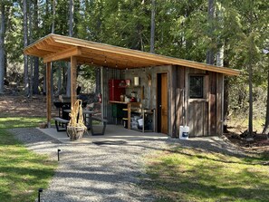 A rustic cabin with a wooden deck, a barbecue area, and a kitchen. - The Raven's Nest Teepee . Nestled in the Selkirk Mountain range, in Naples Idaho (Naples)