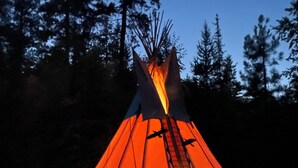 A tipi with a fire inside, surrounded by trees. - The Raven's Nest Teepee . Nestled in the Selkirk Mountain range, in Naples Idaho (Naples)