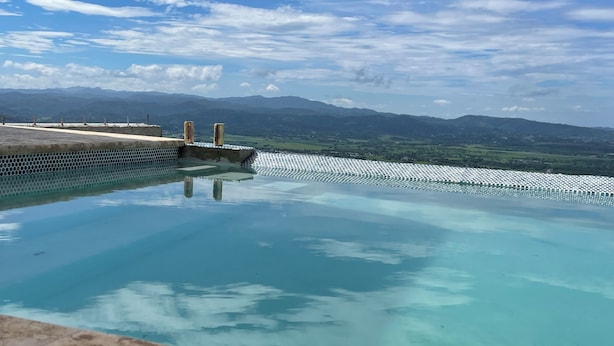 A clear view of a swimming pool with a stone border and a view of distant mountains.