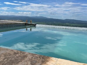 A clear view of a swimming pool with a stone border and a view of distant mountains.