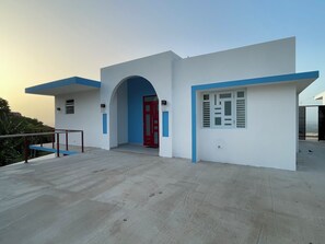 A modern building with a red door, blue accents, and a concrete floor.