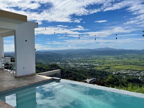 A pool with a view of a town and mountains.