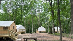 Ein Campingplatz mit Holzhütten, einem Picknicktisch und einem überdachten Bereich.