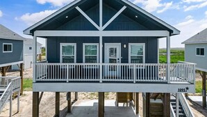 A beachfront house with a balcony, wooden deck, and a number '1095' on the front. - Rare Community Pool! Walk to Beach! Pet Friendly (Bolivar Peninsula)